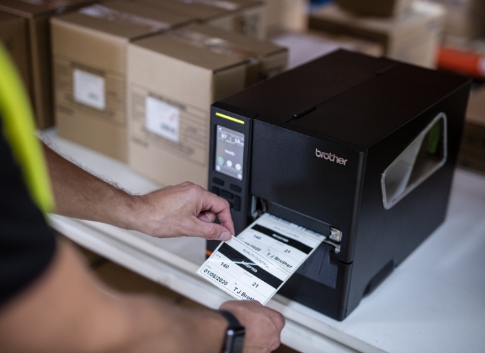 Male Warehouse Associate Taking Label from a Brother Titan Industrial Printer on Shelf