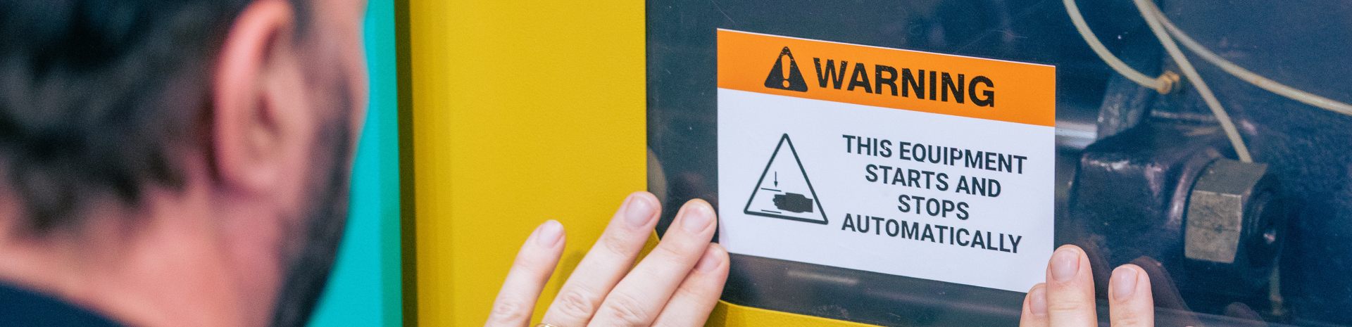 A man inspects a TD 4750TNWBCS, carefully reading a warning that the device starts and stops automatically.