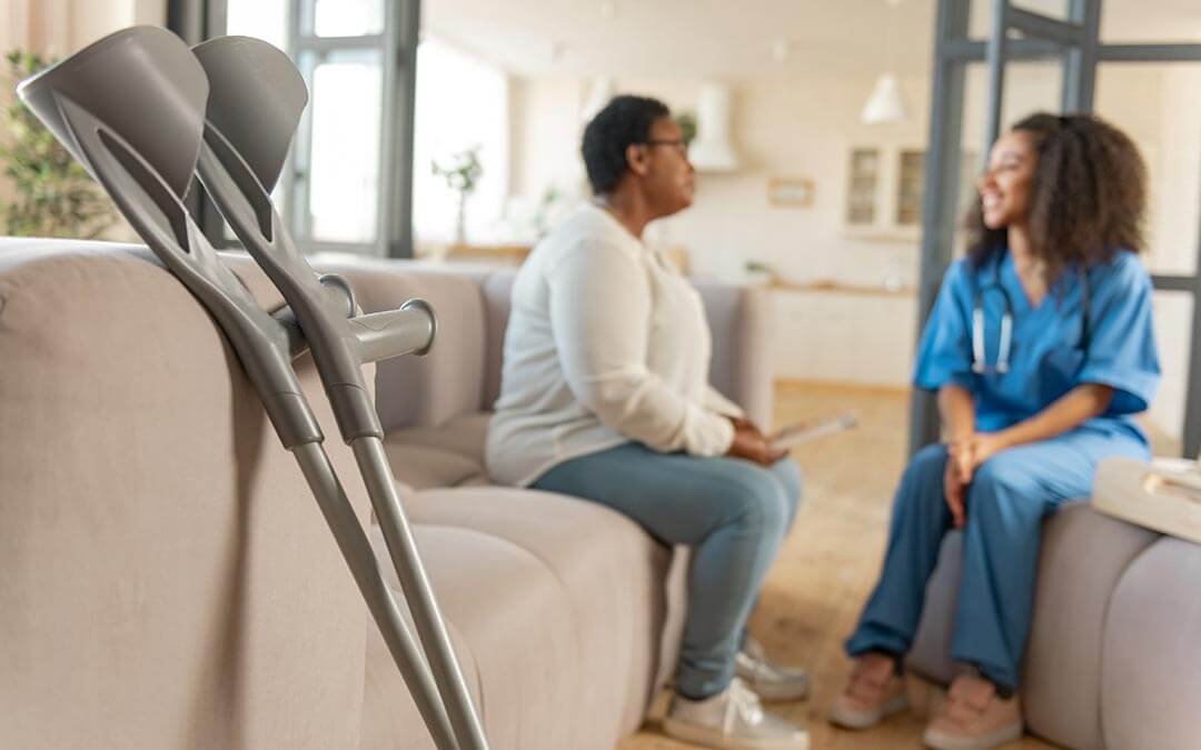 Crutches leaning sofa while patient talks to nurse