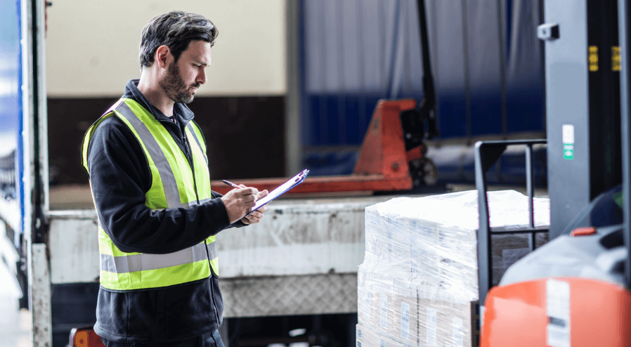 Man wearing safety vest filling out a form on the loading dock