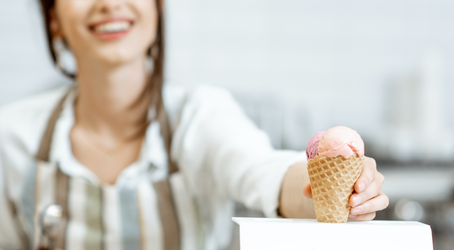 Ice cream worker passing an ice cream cone to a customer