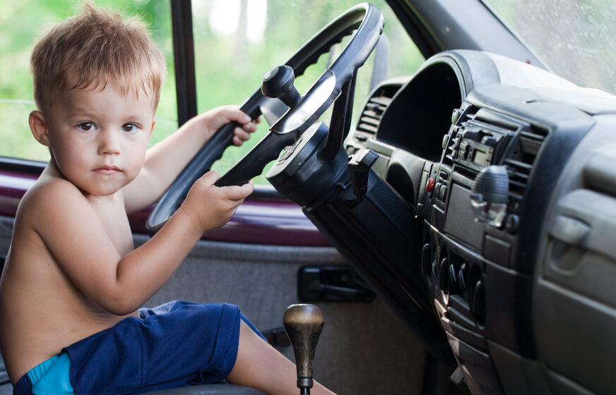 Child sitting in the driver's seat looking at the camera