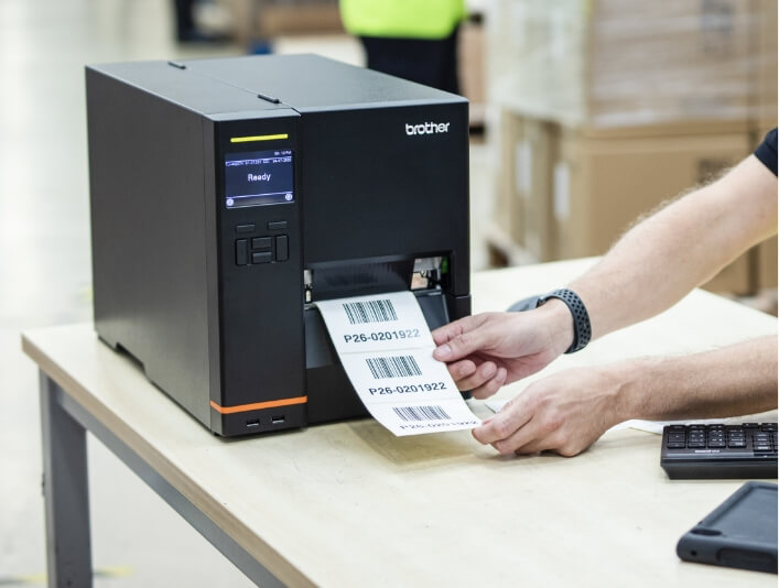 Pair of Hands Holding Labels being Printed on Brother Titan Industrial Printer