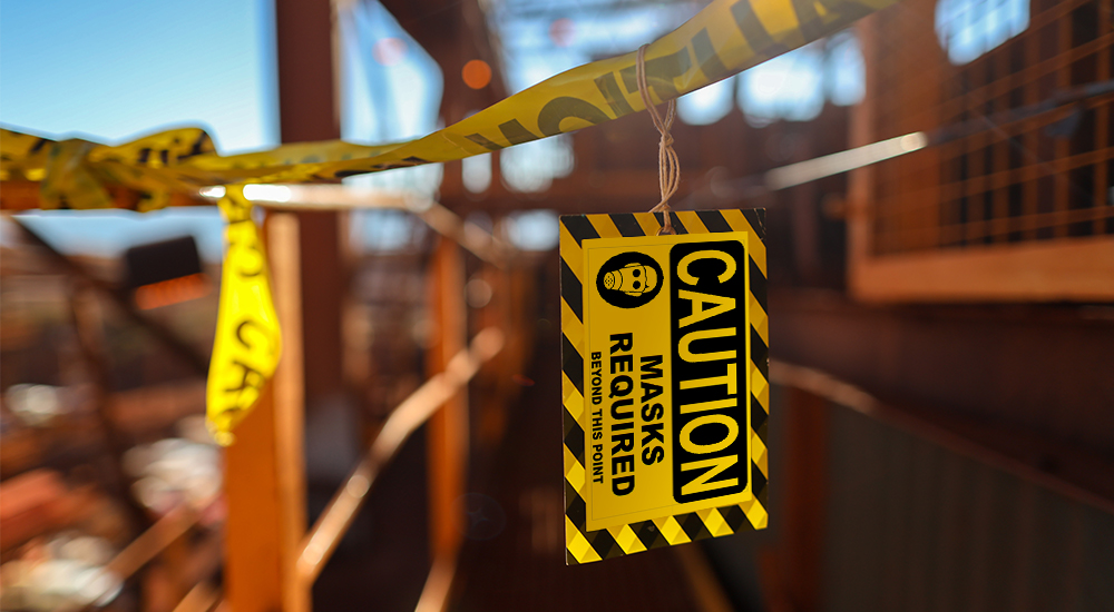 Yellow Caution Masks label hanging from caution tape on construction site