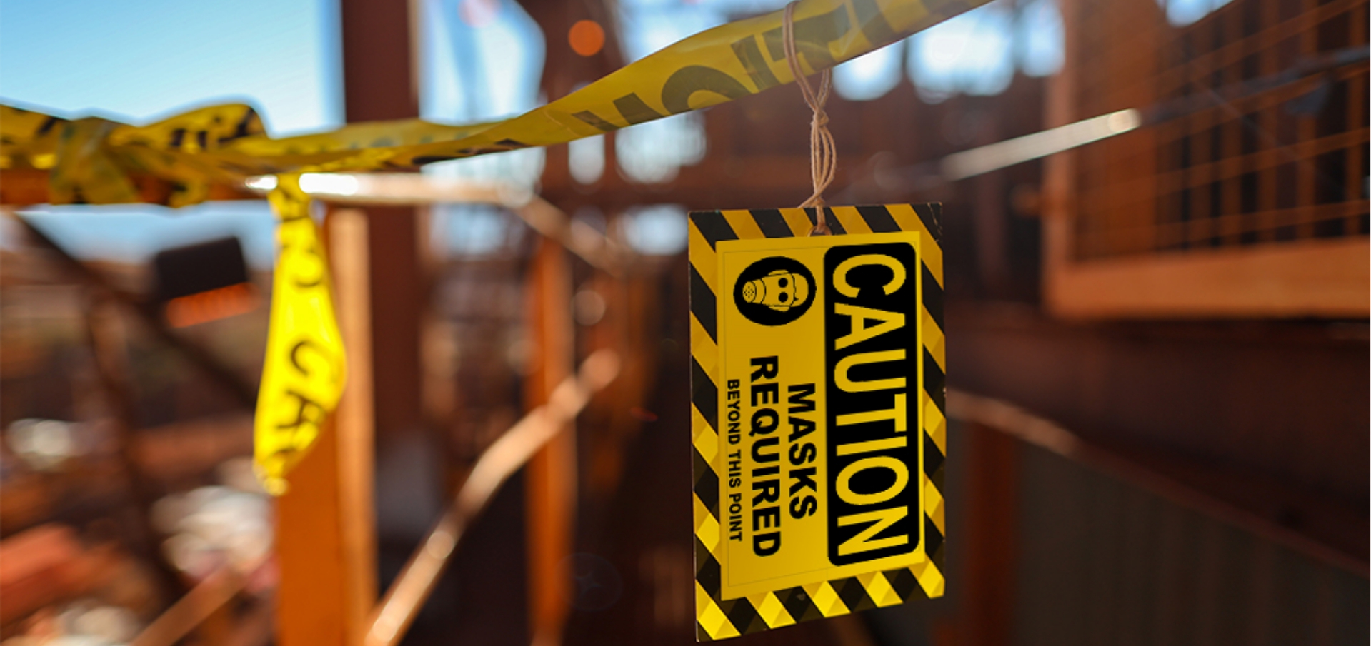 Yellow Caution Masks label hanging from caution tape