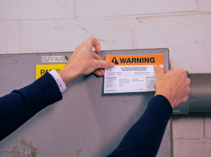 woman applies arc flash sticker