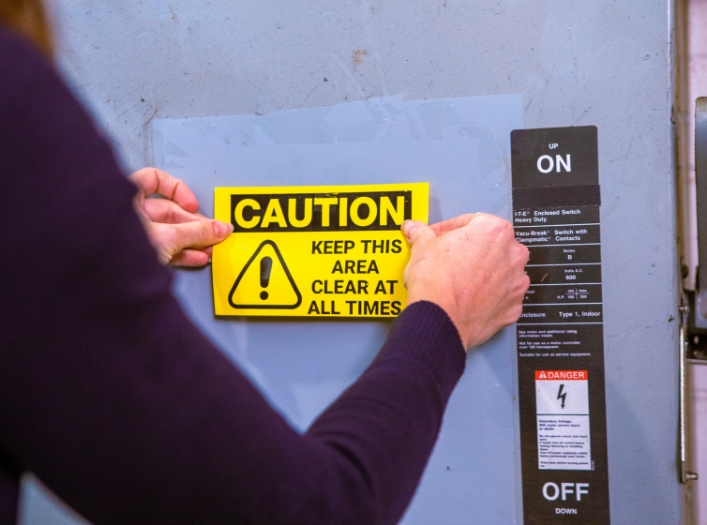 Hands applying OSHA label