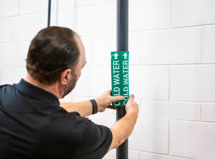 Man applying pipe label