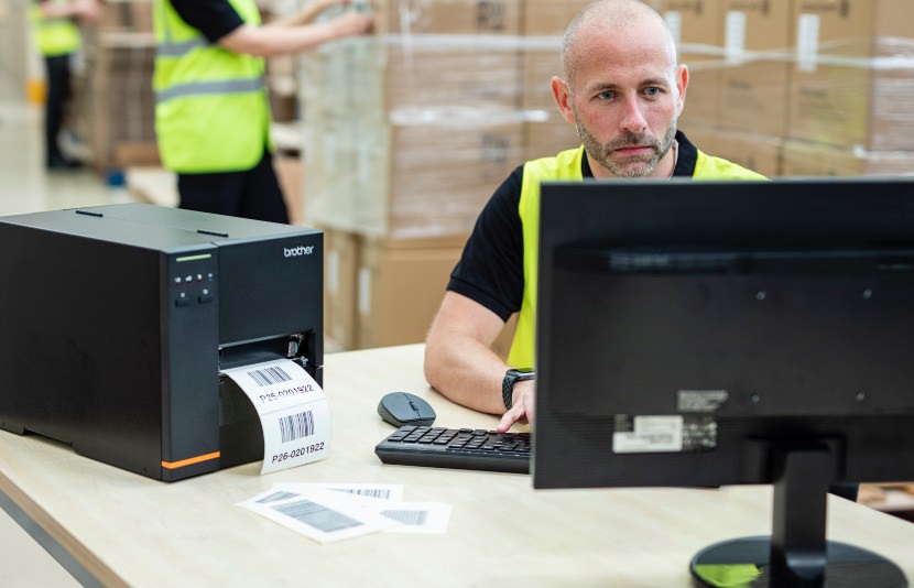 Male warehouse worker uses desktop computer to print wirelessly to Titan Industrial printer