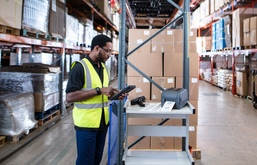 Male warehouse employee using tablet to print labels