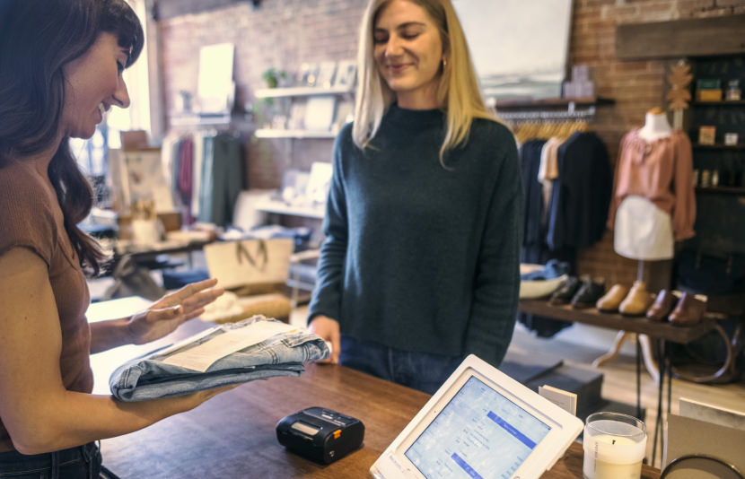 Woman employee handing jeans and receipt to customer