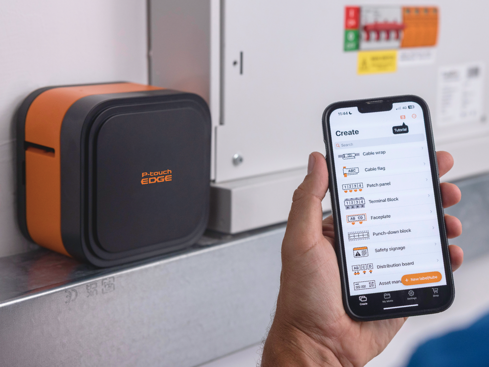 A person uses a smartphone with a label-making app via Bluetooth beside the P-touch EDGE 720BT label printer.
