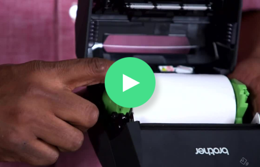 A hand points at the open paper compartment of a Brother RJ4200 label printer, ready for real work.