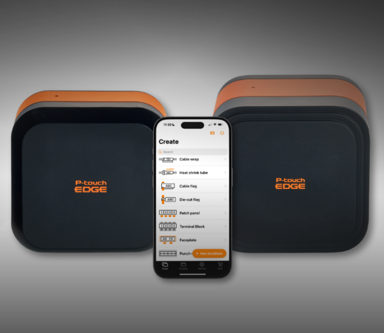 Two black and orange P-touch EDGE devices with a smartphone displaying a label-making app in front of them.