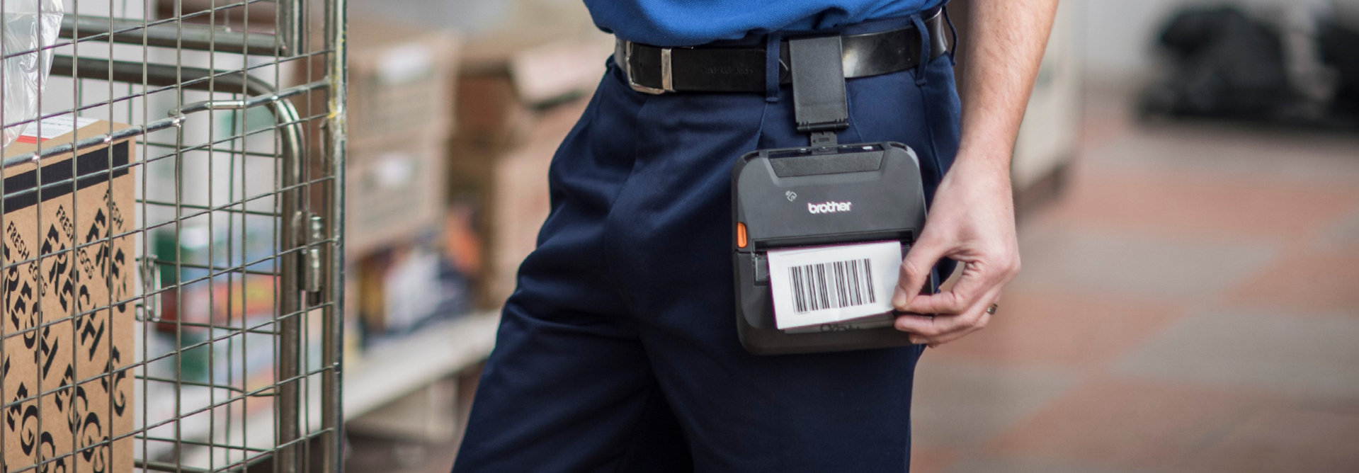 A person in blue pants carries a barcode scanner and has a RuggedJet 4255WB-L mobile printer clipped to their belt.