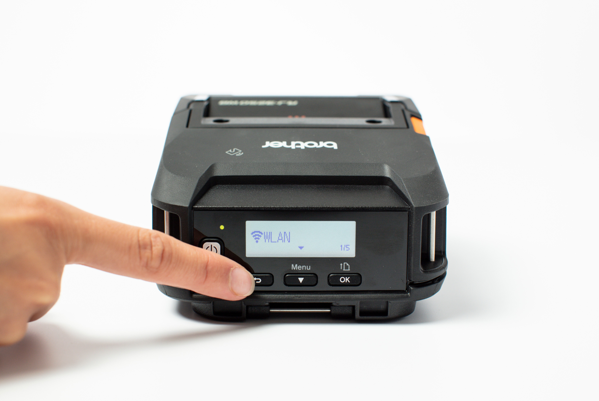 A hand presses a button on a Brother portable printer displaying “WLAN” on its screen.