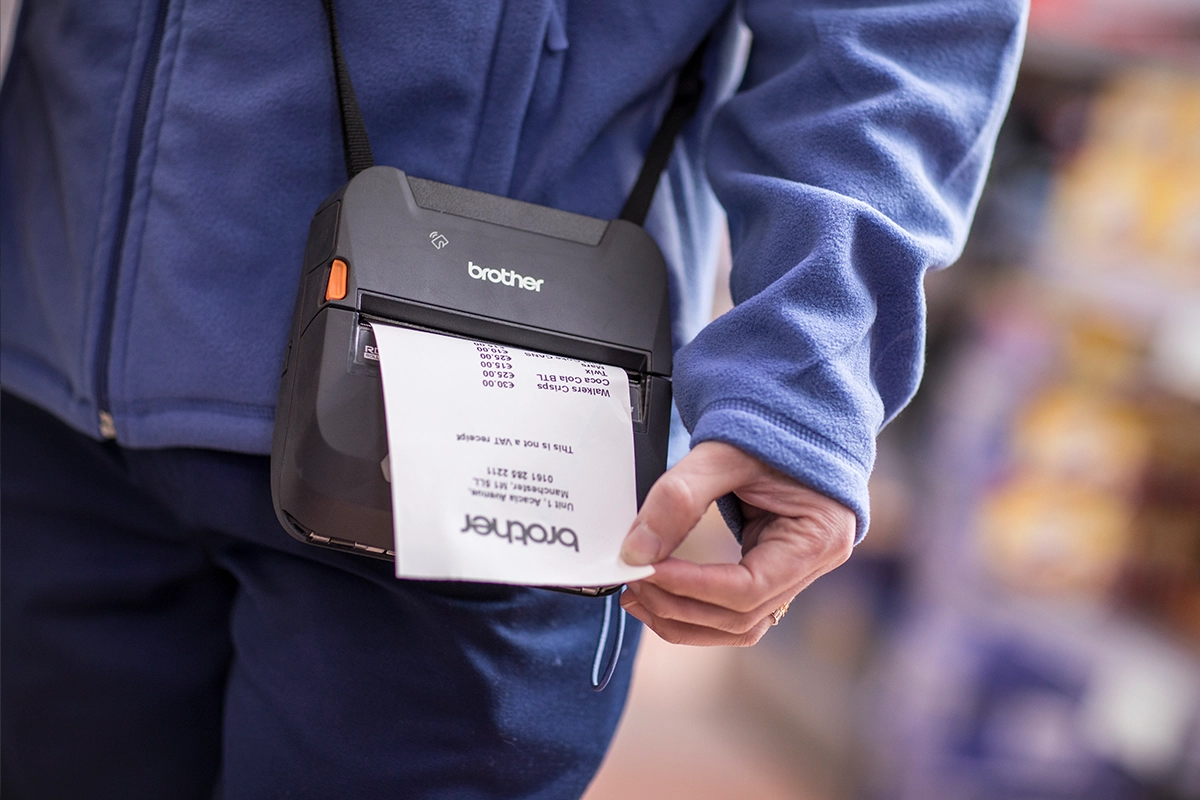 A member of the mobile workforce wears a RuggedJet 4200 portable receipt printer on their waist, pulling out a printed receipt in a store—making smarter upgrades to efficiency and service.