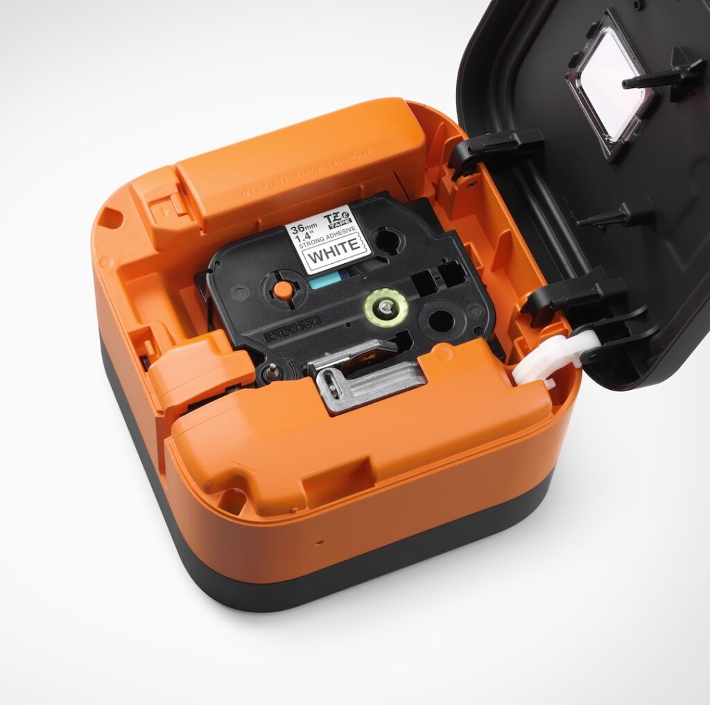 An open orange label printer shows a white label tape cartridge inside—ideal for Industrial Solutions Resellers seeking reliable labeling equipment.